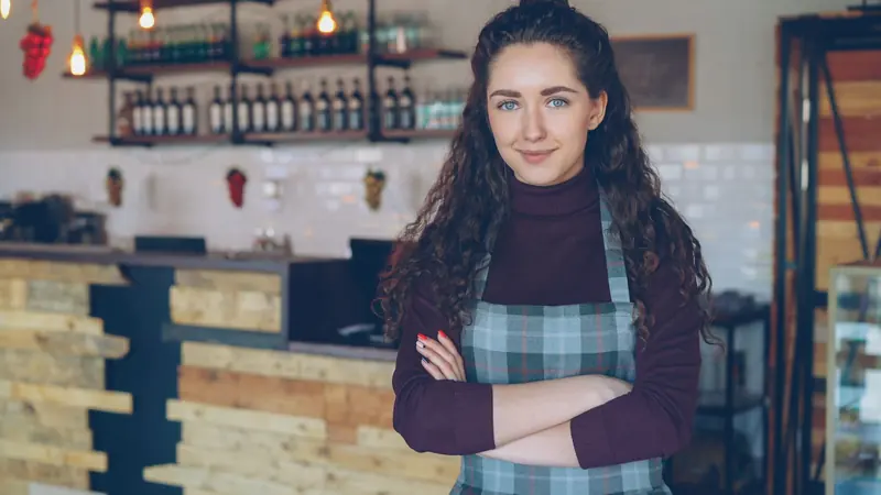 Inhaberin eines Cafés steht lächelnd vor der Theke